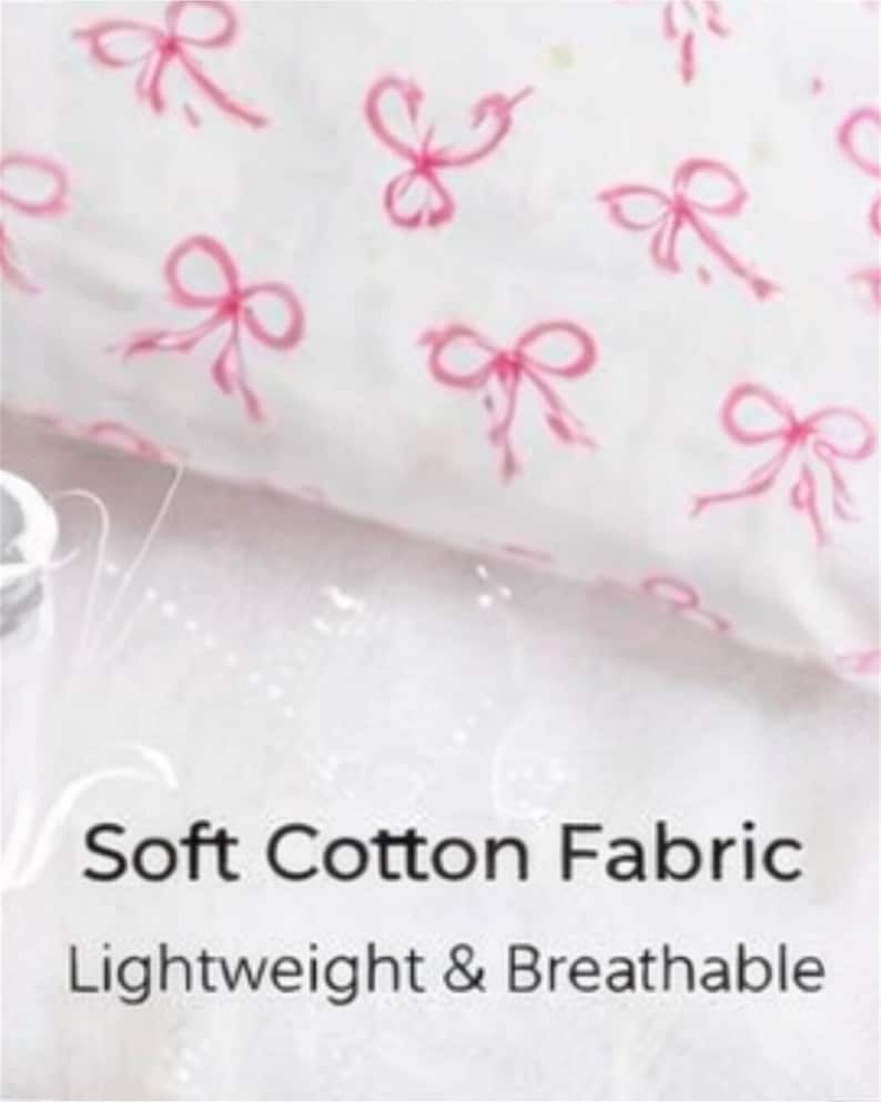May include: White fabric with a repeating pattern of pink bows. The text "Soft Cotton Fabric" and "Lightweight & Breathable" are displayed below the fabric.