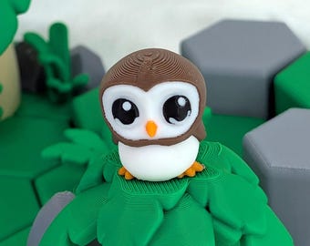 May include: A 3D-printed owl figurine. It has a brown head, large black eyes, and a white chest. The owl is perched on green leaves, with grey and green geometric shapes in the background. The owl has an orange beak.