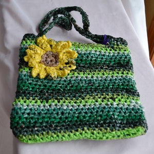 May include: A green and white striped crocheted bag with a yellow crocheted sunflower on the front.