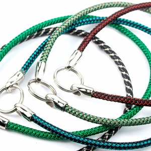 Op de afbeelding: Vier verschillende gekleurde touwhalsters met zilveren metalen gespen en ringen. De halsters zijn groen, zwart en wit, rood en zwart en bruin en wit.