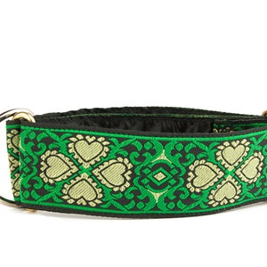 May include: A black and green dog collar with a gold metal buckle and a silver D-ring. The collar has a patterned design with green and gold hearts.