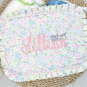 May include: A white fabric burp cloth with a pink floral pattern and the text "simple sweet mama" and "Lillian" embroidered in pink.