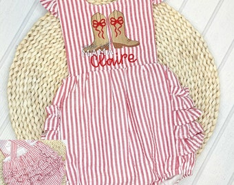 Könnte beinhalten: Rot-weiß gestreiftes Baby-Strampler mit gestickten roten Stiefeln und dem Text "Little Mama Claire". Der Strampler hat Rüschen auf der Rückseite.