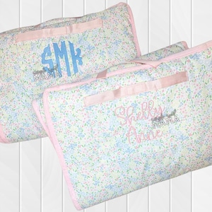 May include: Two floral print quilted baby blankets with pink trim and handles. One blanket has a blue monogram and the word "MAMA" embroidered below. The other blanket has the name "Shelly Anne" embroidered in pink with the word "MAMA" below.