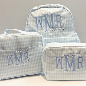 May include: A light blue and white gingham pattern backpack, lunch bag, and cosmetic bag set. Each bag is embroidered with the initials "WMR" and the words "simple sweet MAMA" in light blue thread. The bags are made of a soft fabric.