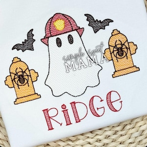 May include: White fabric with an embroidered Halloween design. A ghost wearing a firefighter's hat is surrounded by bats and fire hydrants with spiders. The name "Ridge" is embroidered in red.