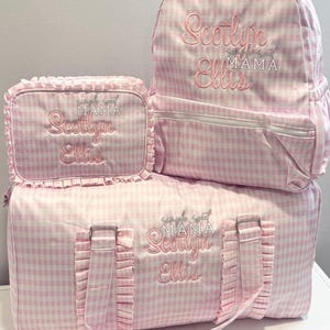 May include: A set of pink and white gingham luggage, including a backpack, a lunch bag, and a duffel bag. Each piece is embroidered with the name "Scotlyn Ellis" and the words "simple sweet MAMA" in pink thread.