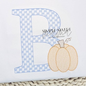 May include: Embroidered letter B with a blue and white checkered pattern and a small orange pumpkin to the right. The text "SIMPLE SWEET" is visible in the background.