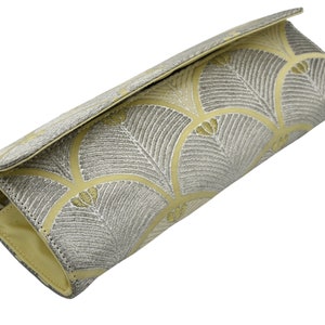May include: A light yellow clutch bag with a silver and gold geometric pattern.