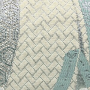 Puede incluir: Primer plano de una tela con fondo blanco y un patr&oacute;n plateado y azul claro. El patr&oacute;n es una combinaci&oacute;n de formas geom&eacute;tricas y dise&ntilde;os florales.