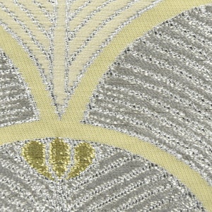 May include: Close-up of a fabric with a silver and yellow geometric pattern. The pattern features overlapping fan shapes with a textured, woven look.