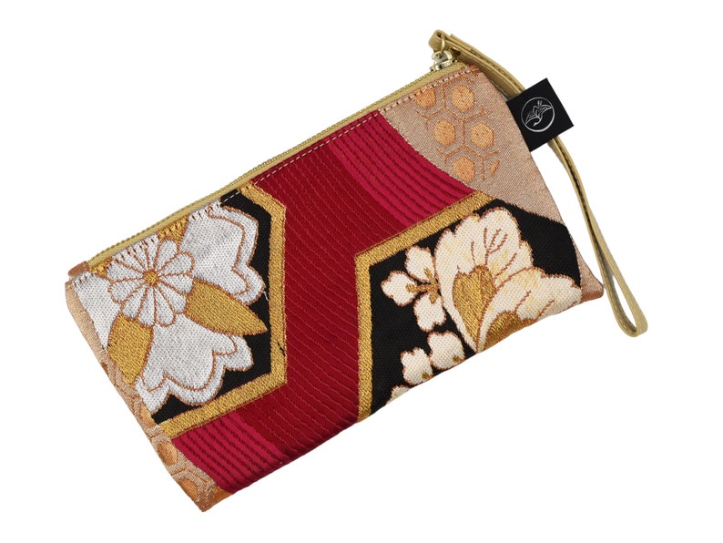 K&ouml;nnte beinhalten: Eine rote, schwarze und goldene Clutch mit floralem Muster und einem goldenen Rei&szlig;verschluss. Die Clutch hat einen langen Riemen.