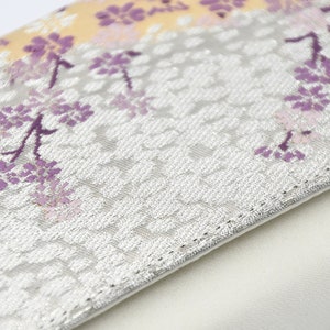 May include: A white clutch purse with a silver floral pattern and a white lining. The floral pattern features purple and pink flowers.