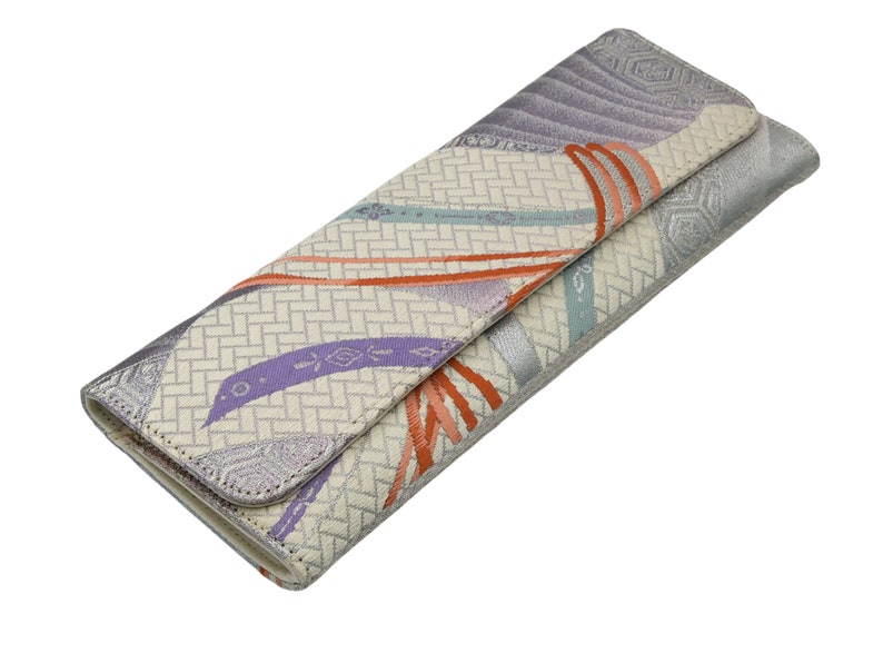 Puede incluir: Un embrague blanco y plateado con un estampado floral colorido. El embrague tiene un cierre de solapa y una cremallera plateada.