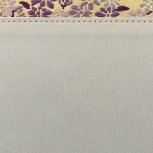 May include: A close-up of a light gray fabric with a subtle texture. The fabric has a stitched seam along the top edge.