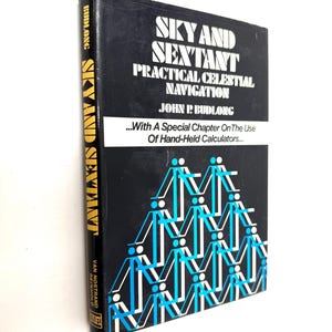 May include: A hardcover book titled "Sky and Sextant: Practical Celestial Navigation" by John P. Budlong. The book has a black cover with white and blue geometric figures and text. The spine reads "Sky and Sextant" in gold.