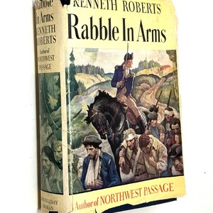 May include: A vintage hardcover book titled "Rabble In Arms" by Kenneth Roberts. The cover features an illustration of a man on horseback leading a group of soldiers. The book is published by Doubleday Doran.