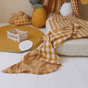 May include: A yellow and white gingham patterned blanket and pillow with a green and yellow pillow and a white leaf on a yellow and blue play mat.