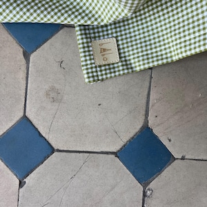 May include: A green and white gingham fabric with a brown leather label that says "BALLO" in white lettering.