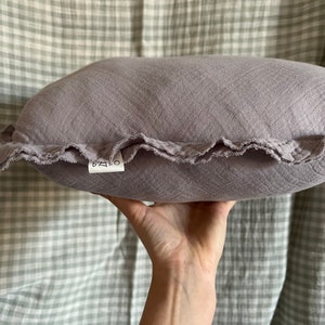 May include: A soft, gray, ruffled pillow with a white label that says "BABO" on it.
