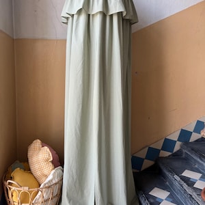 May include: A green and white gingham canopy with a ruffled top. The canopy is hanging from a ceiling hook and is draped over a set of stairs.