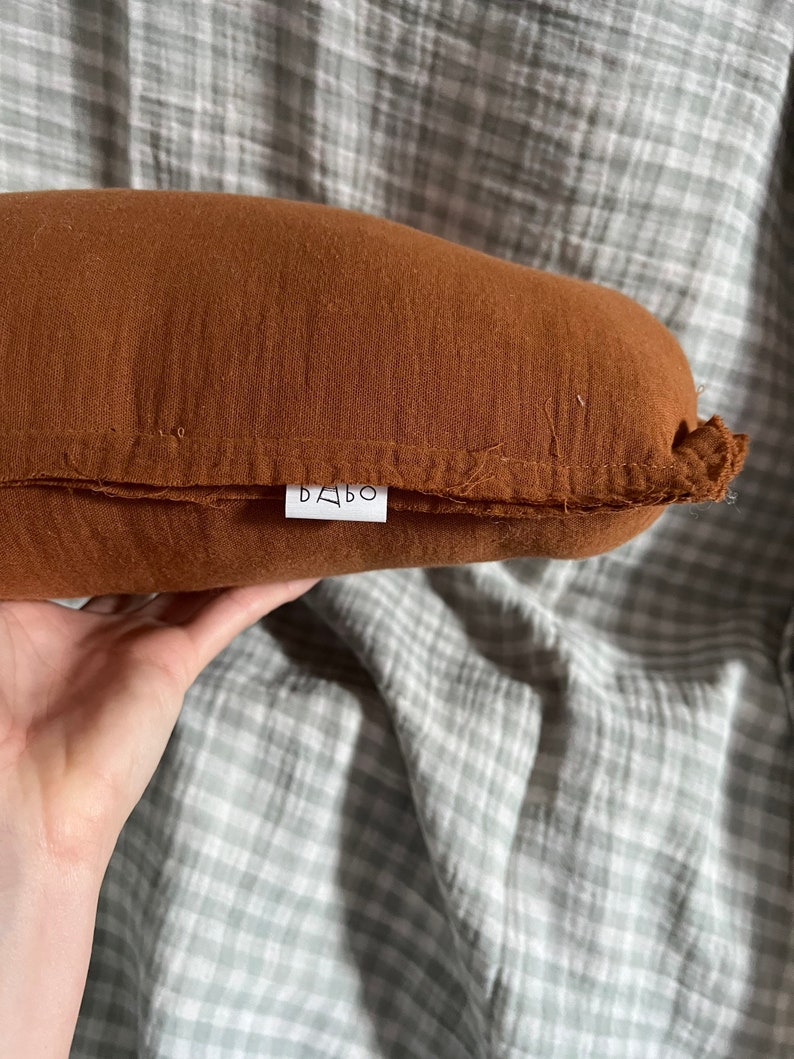 May include: A brown, rectangular pillow with a white label that says "BABO" on it.