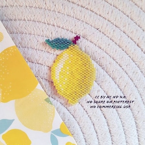 Peut inclure: Un citron jaune perlé avec une feuille verte perlée et une tige rouge perlée. Le citron est sur un fond blanc tissé. Le texte "CC BY NC ND 4.0 NO SHARE ON PINTEREST NO COMMERCIAL USE" est sous le citron.