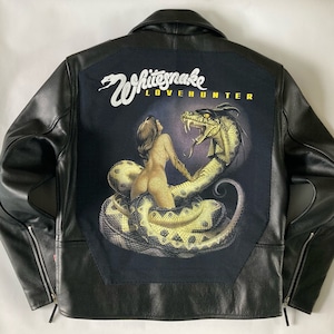 Op de afbeelding: Zwart leren jack met een grote geborduurde patch op de rug. De patch toont een slang die om een vrouw heen is gewikkeld, met de tekst "Whitesnake Lovehunter" erboven.