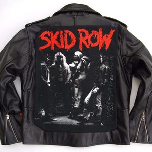 May include: Black leather jacket with a large black and white band patch on the back. The patch features a band of five people with the text "SKID ROW" in red letters.