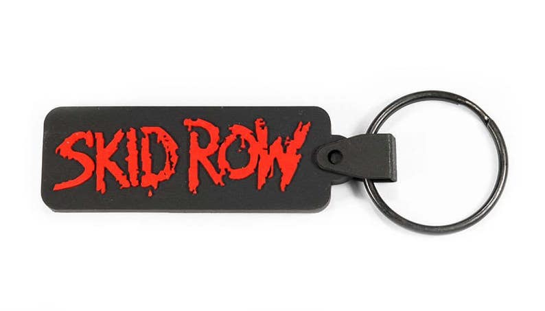 May include: Black rubber keychain with a red "SKID ROW" logo. The keychain has a metal ring.