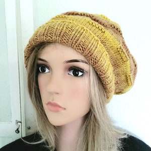May include: A knitted beanie hat with yellow and brown stripes. The hat is slouchy and has a ribbed texture.