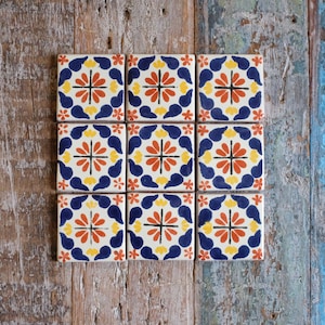 May include: Nine square ceramic tiles with a repeating pattern of blue, yellow and orange flowers. The tiles are arranged in a 3x3 grid.