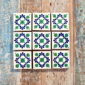 May include: Nine white ceramic tiles with a blue and green floral pattern. The tiles are arranged in a 3x3 grid.