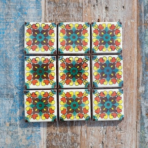 May include: Nine square ceramic tiles with a colourful floral pattern. The tiles are arranged in a 3x3 grid and feature a repeating design of red, yellow, green, and brown flowers.