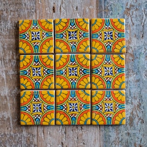 May include: Nine square ceramic tiles with a colourful geometric pattern. The tiles are yellow, orange, blue, green, and white. The pattern is made up of circles, squares, and triangles.