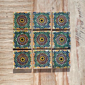 May include: Nine square ceramic tiles featuring a green, blue, yellow and orange mandala design.
