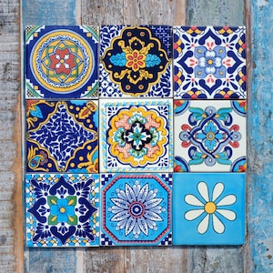 May include: A collection of nine square ceramic tiles arranged in a grid, each featuring distinct geometric and floral patterns in vibrant shades of blue, yellow, red, green, and white, showcasing intricate symmetrical designs and motifs.