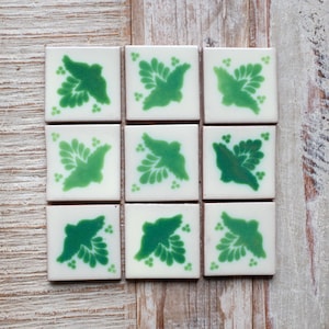 May include: Nine white ceramic tiles with green bird designs. Each tile features a stylised bird with green leaves and a white background.
