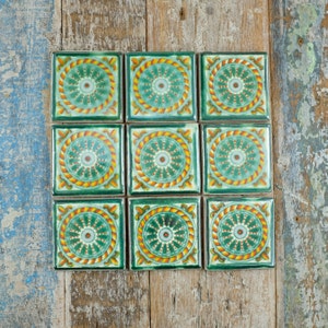 May include: Nine green and yellow ceramic tiles with a circular pattern. The tiles are arranged in a 3x3 grid.