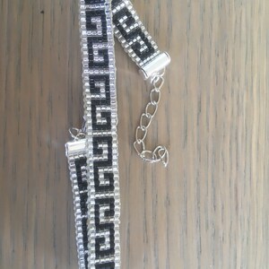 Op de afbeelding: Een zwarte en zilveren kralen armband met een geometrisch patroon. De armband heeft een zilveren sluiting.