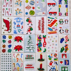 May include: A collection of Christmas-themed stickers featuring angels, ornaments, polar bears, Santa Claus, sleds, penguins, snowflakes, stockings, candy canes, candles, and the text "Merry Christmas".