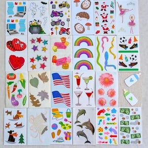 May include: A collection of colorful stickers featuring various designs. Includes images of computers, motorcycles, hearts, stars, rainbows, sports equipment, flags, cocktails, flowers, baby bottles, and more. Perfect for scrapbooking or crafts.