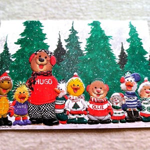May include: A Christmas card featuring a group of cartoon characters in front of a snowy forest scene. The characters include a bear, ducks, and other animals, all wearing winter clothing. The bear is wearing a red sweater with the name "HUGO".