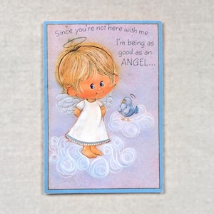 May include: A rectangular greeting card with a light purple background and a blue border. The illustration features a blonde child with angel wings and a halo, wearing a white dress, standing on clouds next to a small blue bird with a halo.