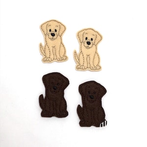 Może przedstawiać: Cztery filcowe łatki z psami, dwie brązowe i dwie beżowe, z czarnymi haftowanymi detalami. Łatki są w pozycji siedzącej z podwiniętymi ogonami.