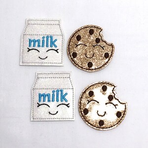 May include: Two embroidered patches, one a white milk carton with the word "milk" and a smiling face, the other a brown chocolate chip cookie with a bite taken out and a smiling face.