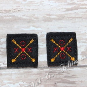 以下が含まれることがあります： 金色の矢印と赤いハートが刺繍された黒いフェルトの正方形が2つ。正方形は、約2.5cm×2.5cmです。