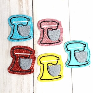 May include: Five felt kitchen mixer appliques in different colors: light blue, pink, red, yellow, and turquoise. Each applique has a silver bowl and a black outline.