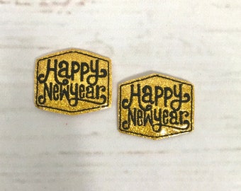 Puede incluir: Dos parches de planchado de purpurina dorada con bordado negro que dice "Happy New Year".