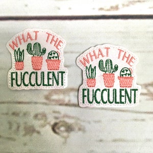 May include: Two white iron-on patches with green and pink embroidery. The patches feature the text "What the Fucclulent" with three potted cactus plants.